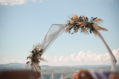 Salle voûtée en pierre avec une table ronde dressée, ornée de fleurs blanches et serviettes pliées bleues.
