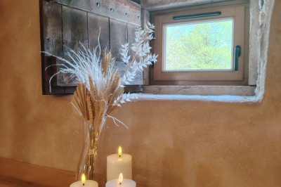 Salle voûtée en pierre avec une table ronde dressée, ornée de fleurs blanches et serviettes pliées bleues.