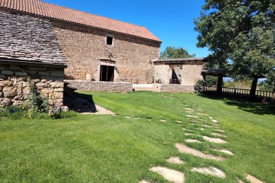 Chambre avec murs en pierre, lit double avec couverture blanche et cheminée ancienne en pierre.