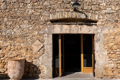 Chambre avec murs en pierre, lit double avec couverture blanche et cheminée ancienne en pierre.