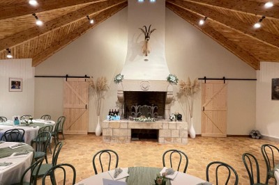 Espace extérieur avec tables hautes dressées et une cabane en bois, entouré d'arbres dans un cadre naturel.