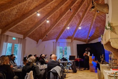 Espace extérieur avec tables hautes dressées et une cabane en bois, entouré d'arbres dans un cadre naturel.
