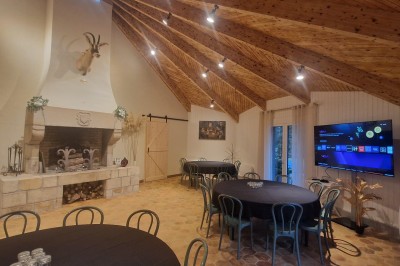 Espace extérieur avec tables hautes dressées et une cabane en bois, entouré d'arbres dans un cadre naturel.