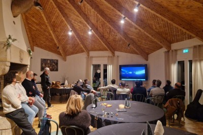 Espace extérieur avec tables hautes dressées et une cabane en bois, entouré d'arbres dans un cadre naturel.