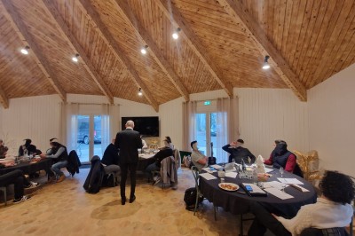Espace extérieur avec tables hautes dressées et une cabane en bois, entouré d'arbres dans un cadre naturel.