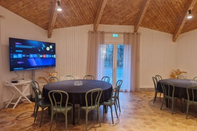 Espace extérieur avec tables hautes dressées et une cabane en bois, entouré d'arbres dans un cadre naturel.