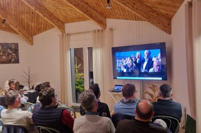 Espace extérieur avec tables hautes dressées et une cabane en bois, entouré d'arbres dans un cadre naturel.