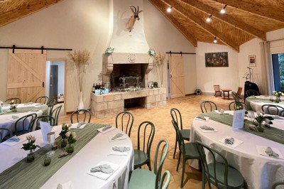 Espace extérieur avec tables hautes dressées et une cabane en bois, entouré d'arbres dans un cadre naturel.