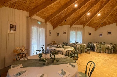 Espace extérieur avec tables hautes dressées et une cabane en bois, entouré d'arbres dans un cadre naturel.