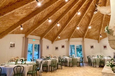 Espace extérieur avec tables hautes dressées et une cabane en bois, entouré d'arbres dans un cadre naturel.