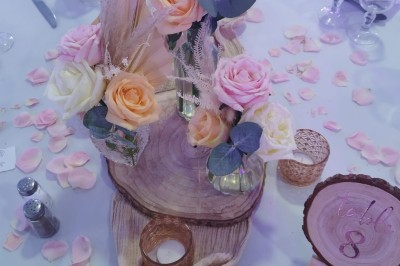 Salle de réception spacieuse avec tables rondes dressées, chaises blanches et éclairage doux.