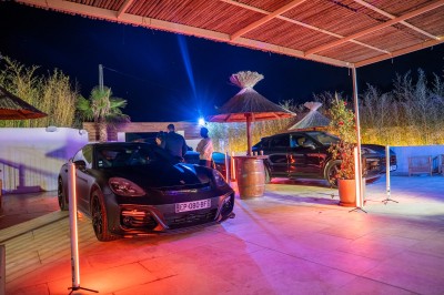 Salle de réception spacieuse avec tables rondes dressées, chaises blanches et éclairage doux.