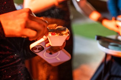Salle de réception spacieuse avec tables rondes dressées, chaises blanches et éclairage doux.