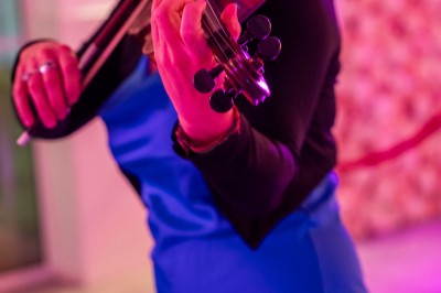 Salle de réception spacieuse avec tables rondes dressées, chaises blanches et éclairage doux.