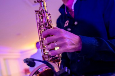 Salle de réception spacieuse avec tables rondes dressées, chaises blanches et éclairage doux.