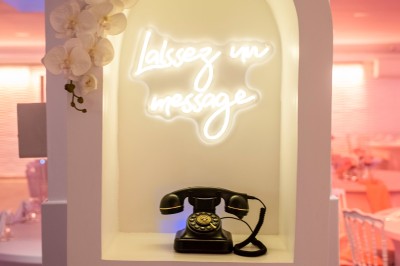 Salle de réception spacieuse avec tables rondes dressées, chaises blanches et éclairage doux.
