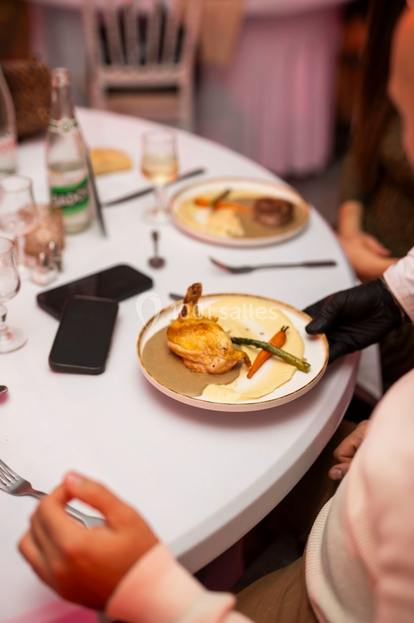 Une assiette contenant du poulet rôti, des légumes et une sauce est servie à une table dressée.