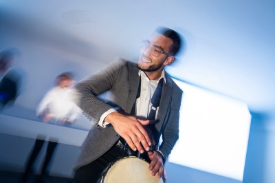 Salle de réception spacieuse avec tables rondes dressées, chaises blanches et éclairage doux.