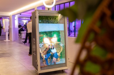 Salle de réception spacieuse avec tables rondes dressées, chaises blanches et éclairage doux.