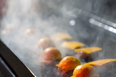 Salle de réception spacieuse avec tables rondes dressées, chaises blanches et éclairage doux.