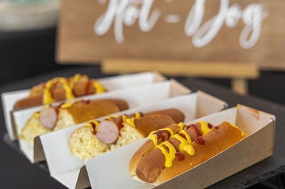 Salle de réception spacieuse avec tables rondes dressées, chaises blanches et éclairage doux.