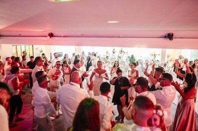 Salle de réception spacieuse avec tables rondes dressées, chaises blanches et éclairage doux.