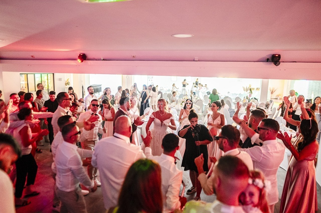 Groupe de personnes dansant et célébrant dans une salle lumineuse lors d'un événement festif.