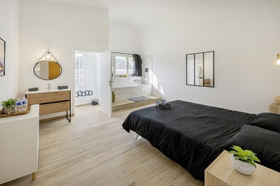 Salle de réception spacieuse avec tables rondes dressées, chaises blanches et éclairage doux.