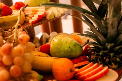 Salle de réception spacieuse avec tables rondes dressées, chaises blanches et éclairage doux.