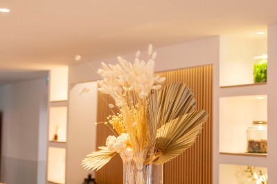 Salle de réception spacieuse avec tables rondes dressées, chaises blanches et éclairage doux.