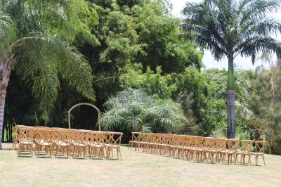 Chambre lumineuse avec lit à baldaquin, décoration tropicale, grandes fenêtres ouvertes sur une terrasse verdoyante.