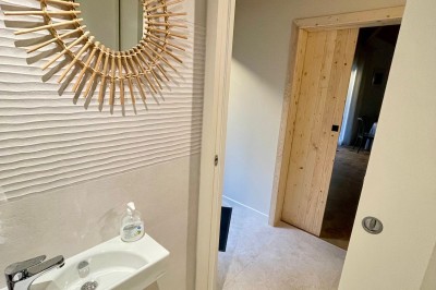 Chemin ombragé bordé de grands arbres et de buissons fleuris de fleurs violettes dans un parc verdoyant.