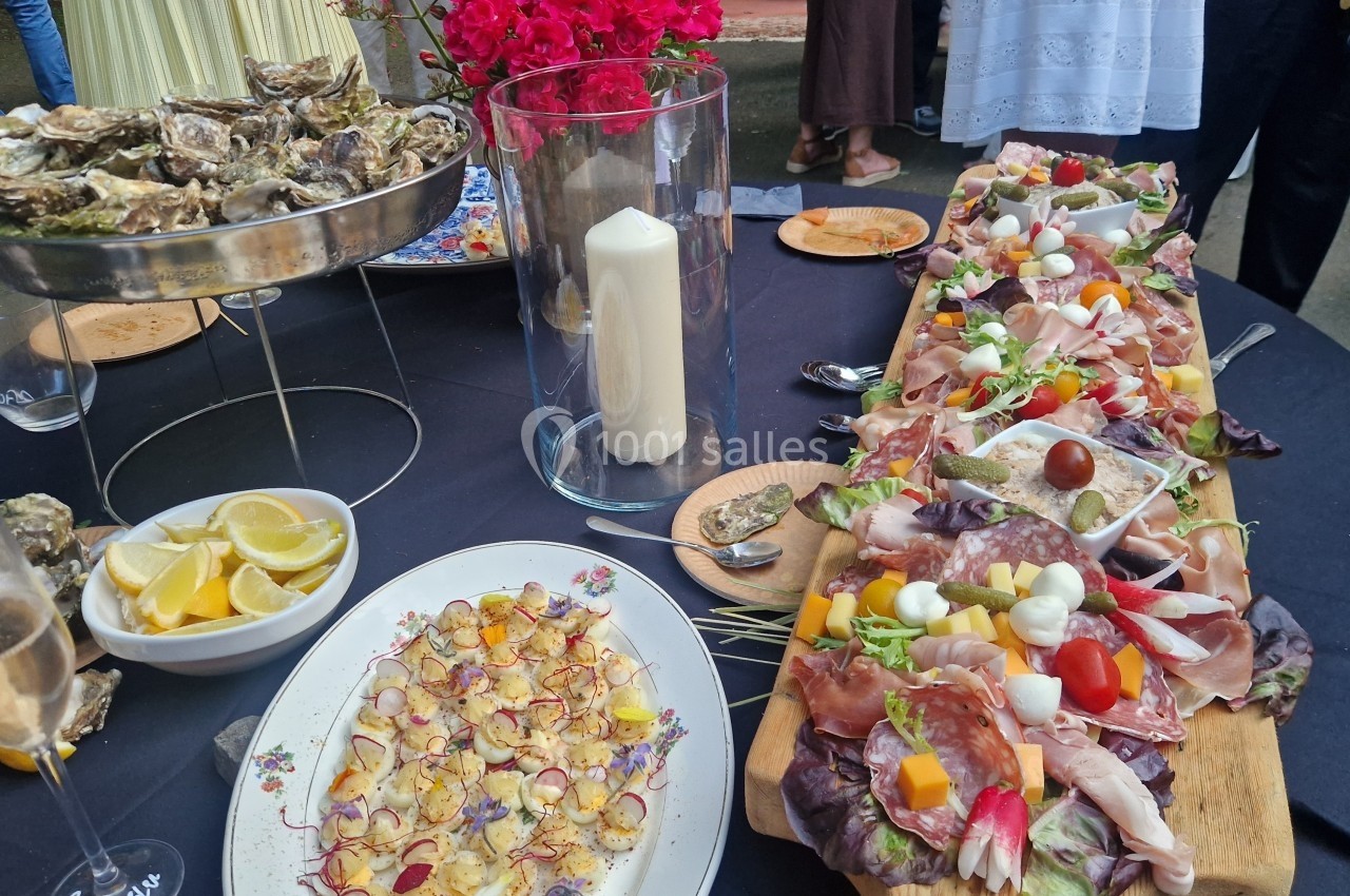 Plateau de charcuterie, fromages et légumes, avec huîtres, citron et bougie décorative sur une table de réception.
