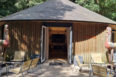 Miniature Entrée du pavillon Sculpture colorée en forme d'oiseau devant un bâtiment en bois avec l'inscription ’Bois des Guillemins’.