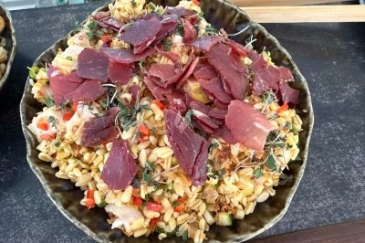 Tour de choux garnis, assemblés avec du caramel et décorés de fleurs en sucre roses et bleues.