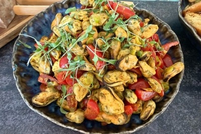 Tour de choux garnis, assemblés avec du caramel et décorés de fleurs en sucre roses et bleues.