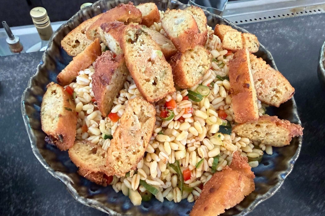 Salade de pâtes orzo garnie de croûtons dorés et de légumes colorés, servie dans un plat en céramique.