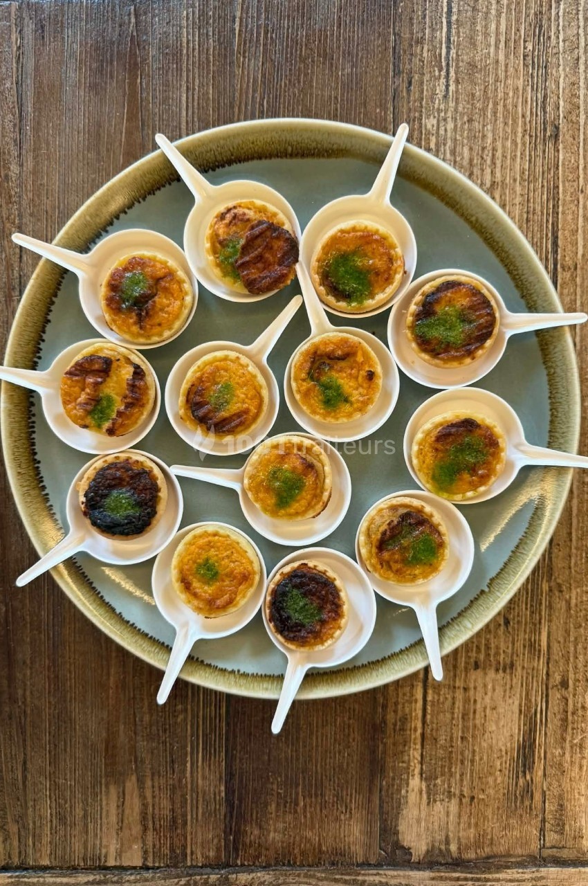 Petites portions de crème brûlée servies dans des cuillères blanches sur une assiette ronde en bois.