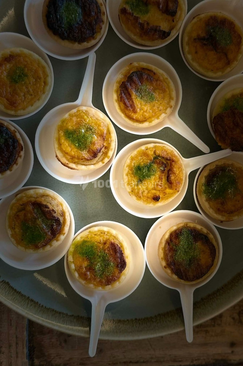 Petites portions de crème brûlée servies dans des cuillères blanches, garnies d'herbes vertes.