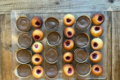 Tour de choux garnis, assemblés avec du caramel et décorés de fleurs en sucre roses et bleues.