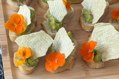 Tour de choux garnis, assemblés avec du caramel et décorés de fleurs en sucre roses et bleues.
