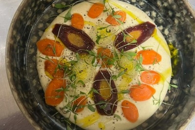 Tour de choux garnis, assemblés avec du caramel et décorés de fleurs en sucre roses et bleues.