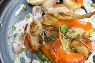 Tour de choux garnis, assemblés avec du caramel et décorés de fleurs en sucre roses et bleues.