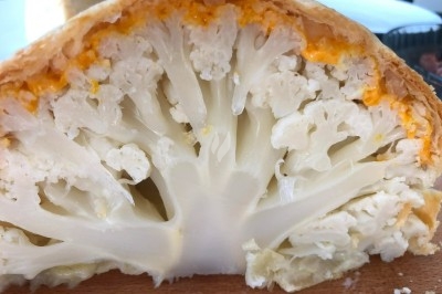 Tour de choux garnis, assemblés avec du caramel et décorés de fleurs en sucre roses et bleues.