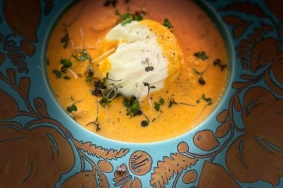 Tour de choux garnis, assemblés avec du caramel et décorés de fleurs en sucre roses et bleues.