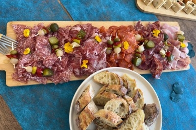 Plateaux en bois avec fromages suisses, petits pains garnis et amuse-bouches décorés de fleurs comestibles.