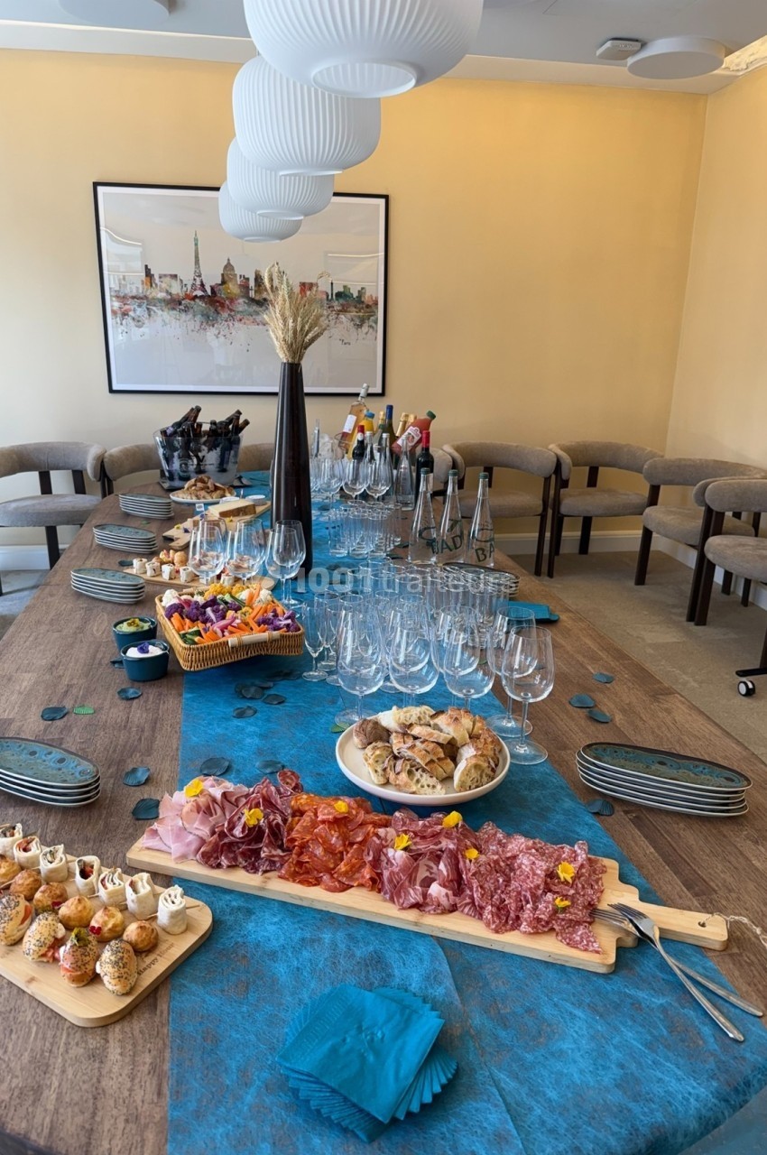 Table dressée avec planches de charcuterie, amuse-bouches, verres à vin et bouteilles dans une salle lumineuse.