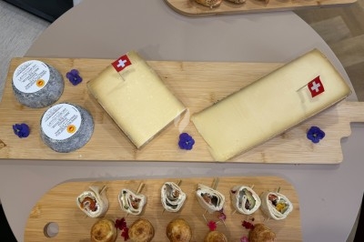 Plateaux en bois avec fromages suisses, petits pains garnis et amuse-bouches décorés de fleurs comestibles.