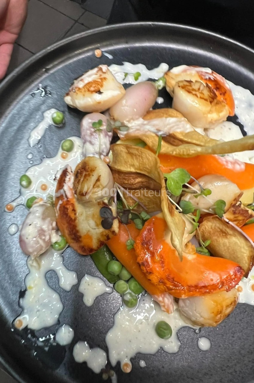 Assiette gastronomique avec noix de Saint-Jacques, légumes colorés, chips croustillantes et sauce crémeuse.