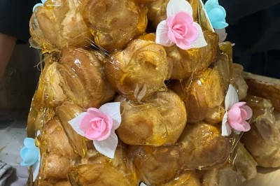 Tour de choux caramélisés décorée de fleurs en sucre roses et bleues, assemblée pour un dessert festif.